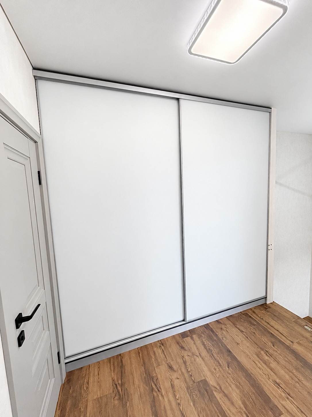 Matte white sliding doors on a built-in wardrobe